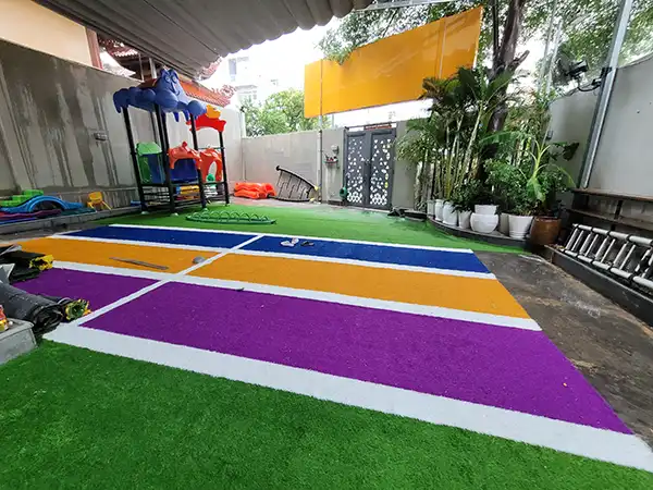 Thảm cỏ nhân tạo màu xanh dương, vàng, tím trải trường học